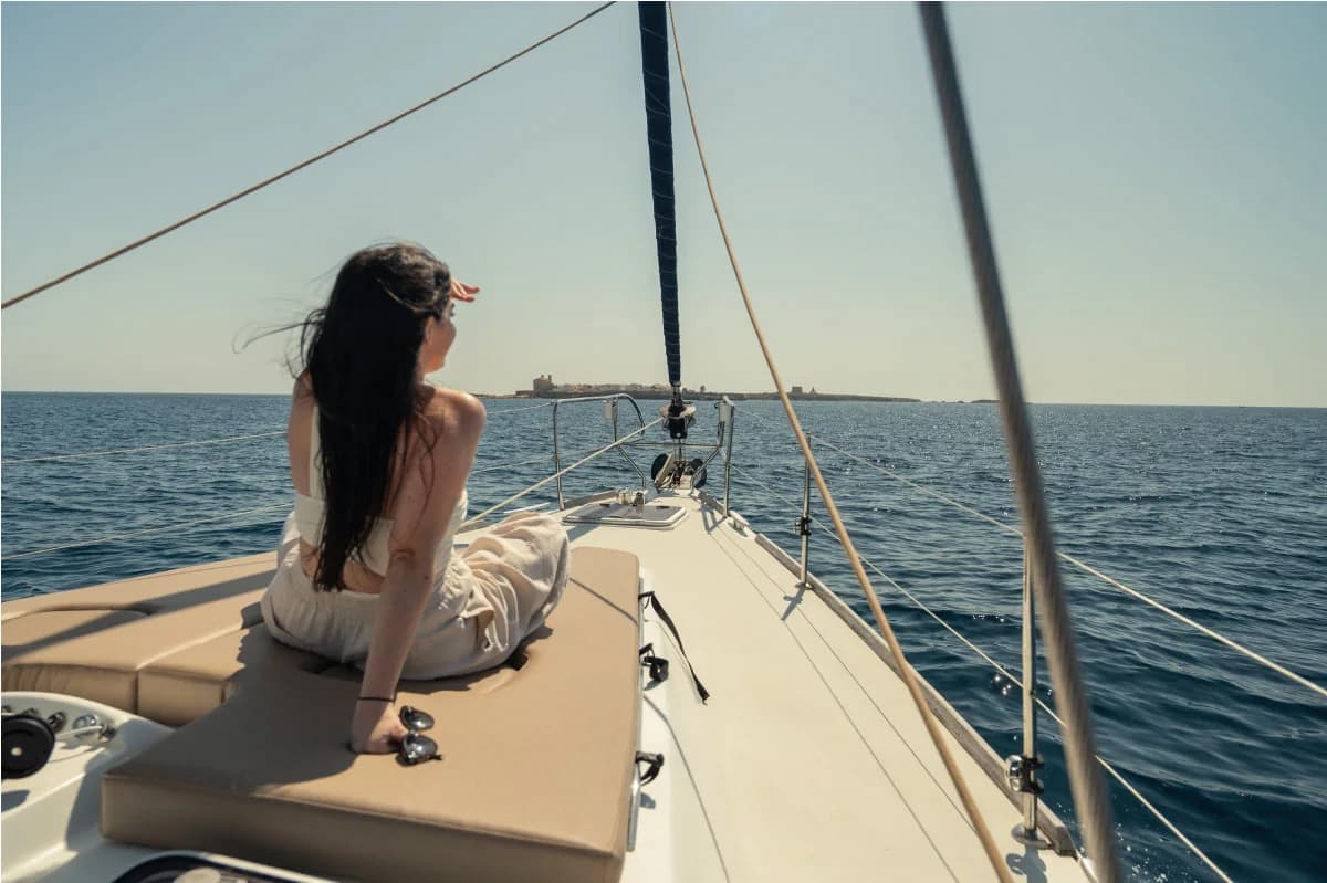 Guest relaxing on the bow of the Candela sailing yacht while approaching Tabarca Island